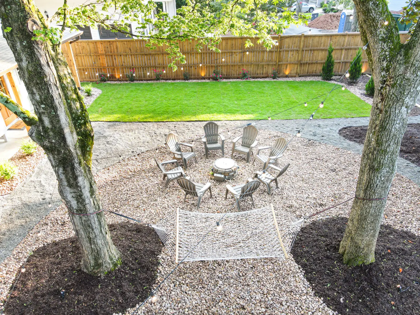 Gravel fire pit area and hammock between two shade trees