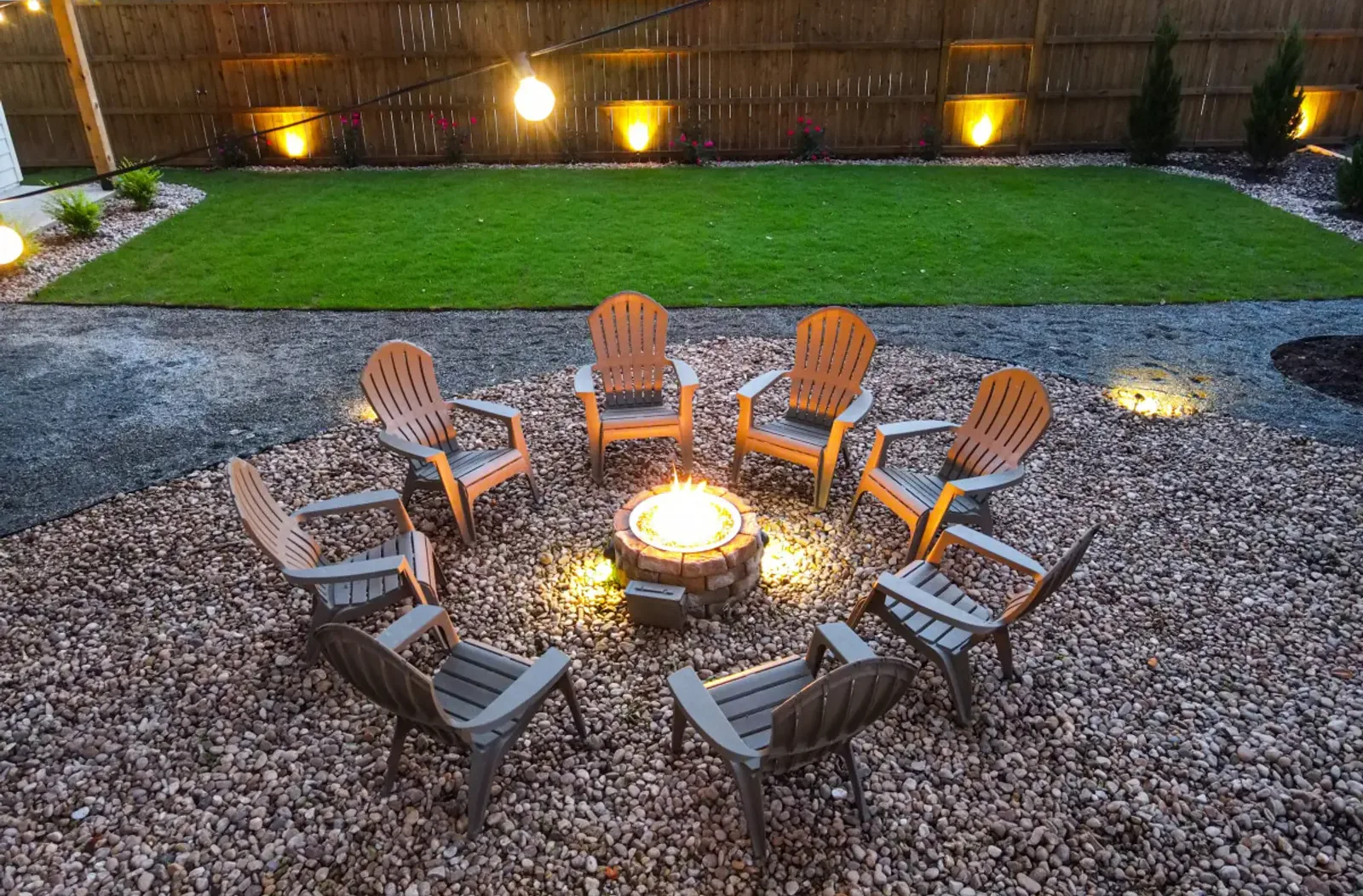 String-lit backyard with the fire pit and lawn at night
